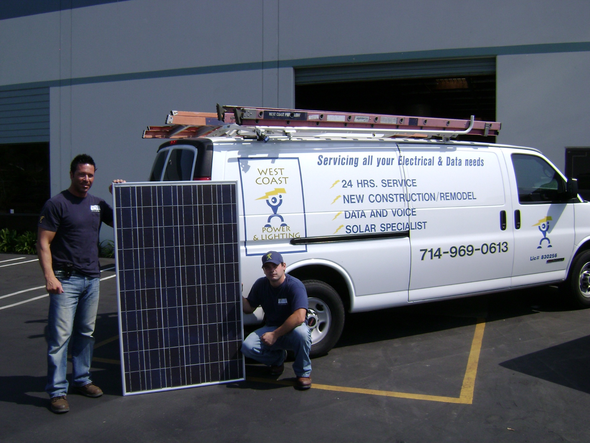West Coast Power & Lighting team with a solar panel in front of the company service van