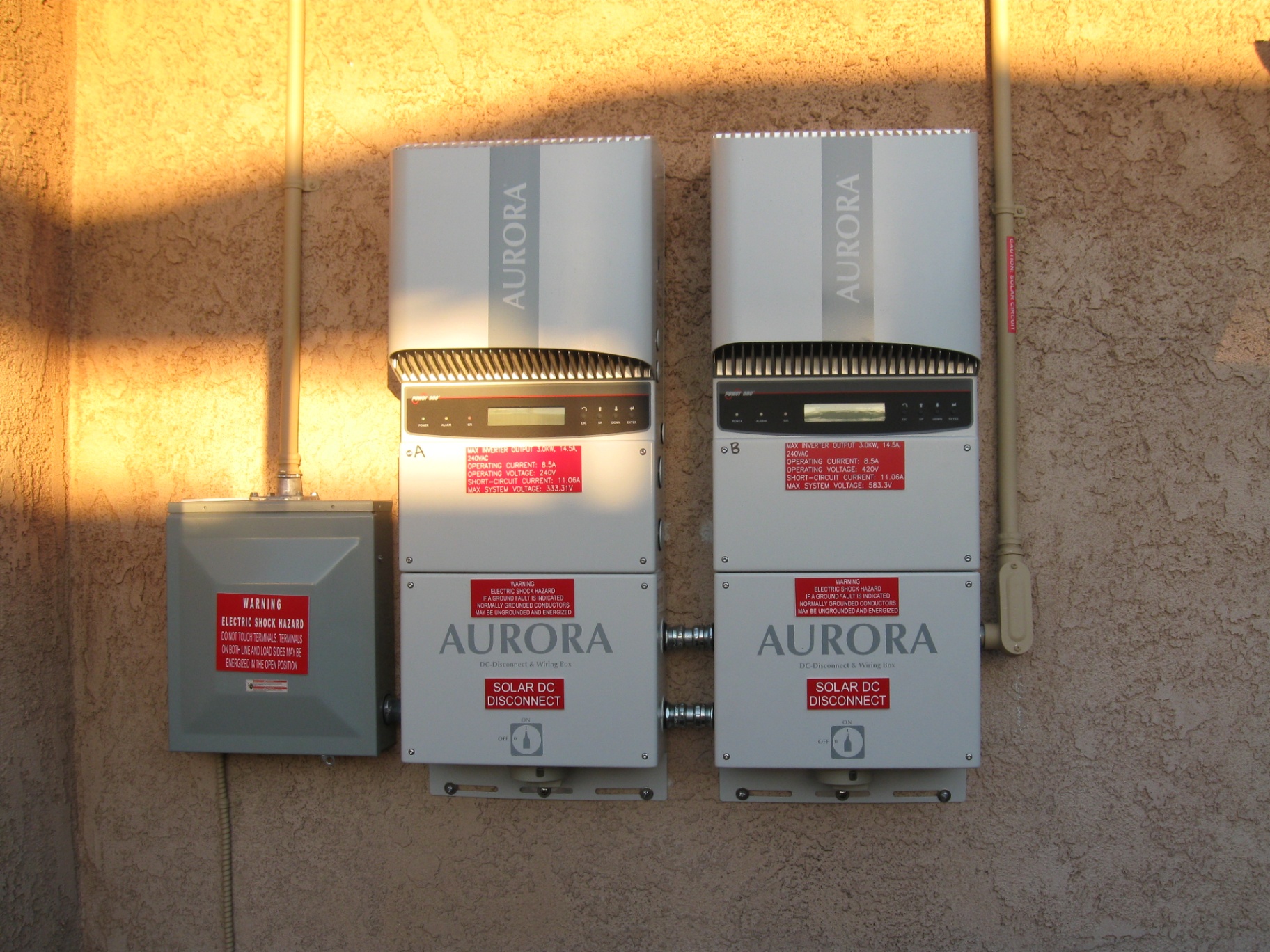 Pair of Power-One Aurora string inverters with DC disconnect wiring boxes mounted on a stucco exterior wall