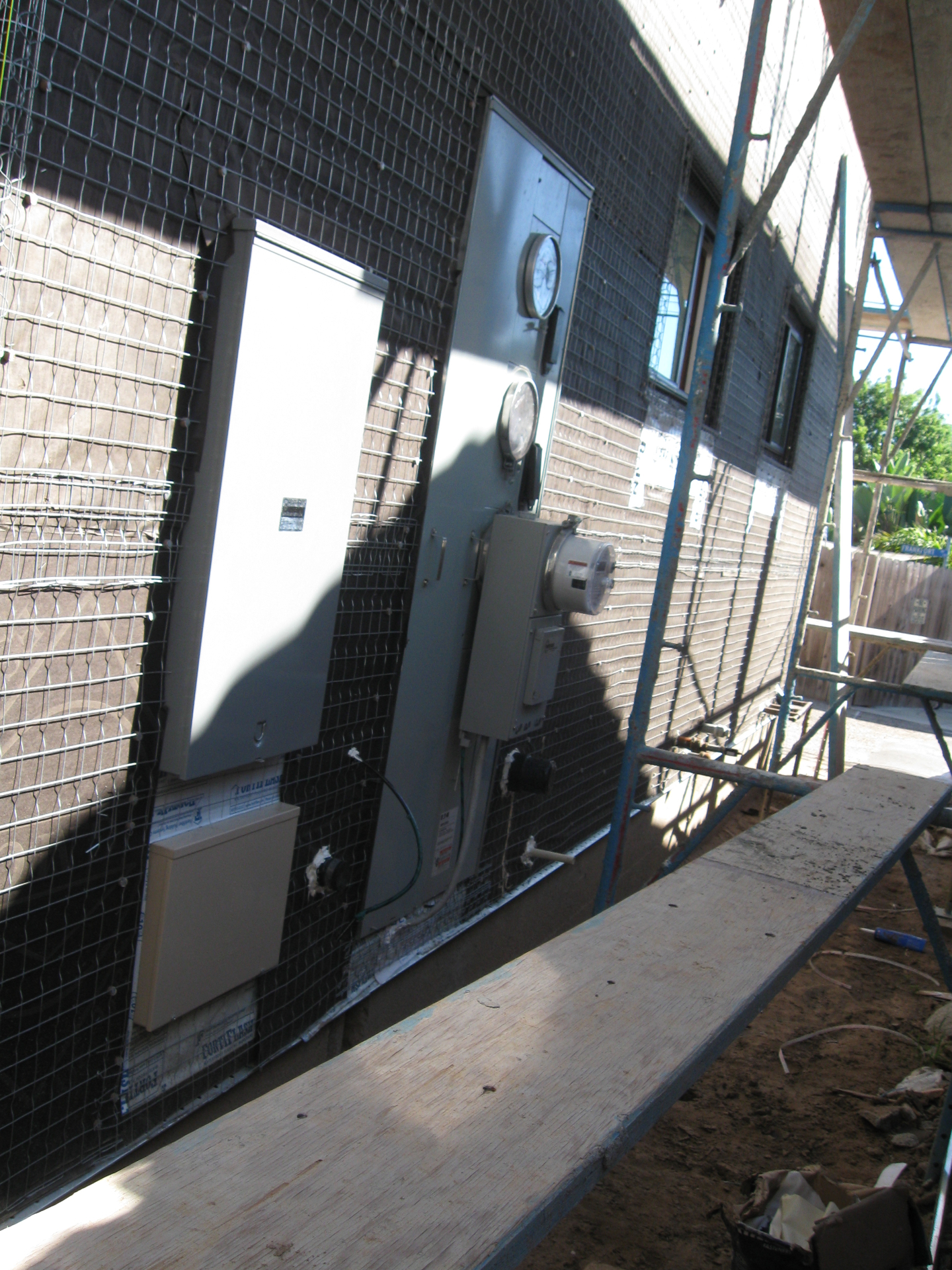Exterior main service panel, utility meter, and sub-panel rough-in on a custom Huntington Beach home during construction