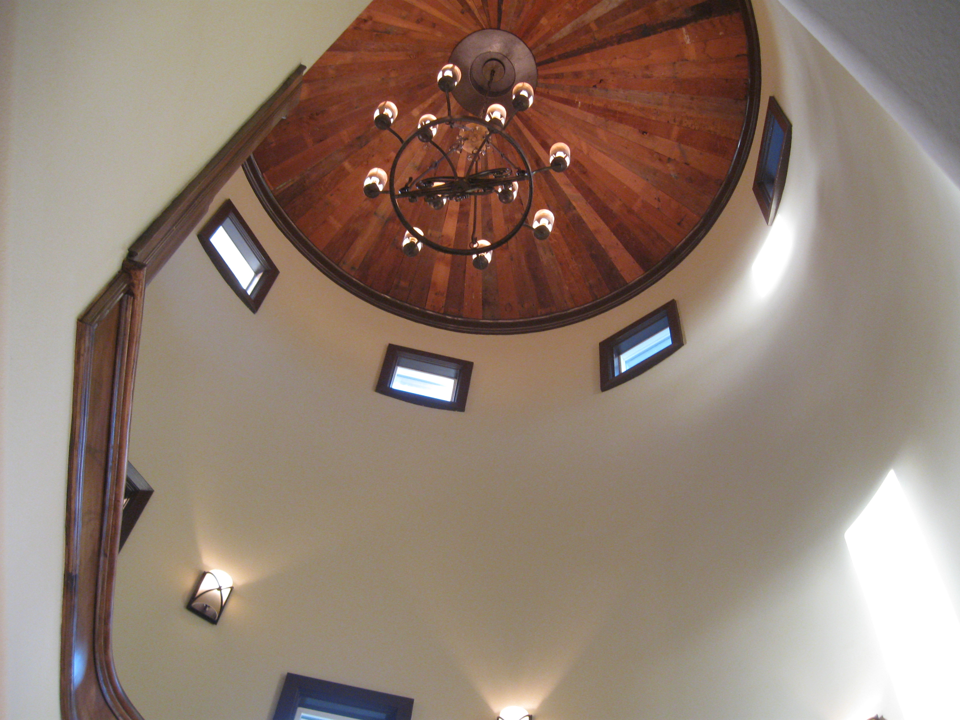 Two-story wood dome ceiling with wrought-iron chandelier in a custom home foyer