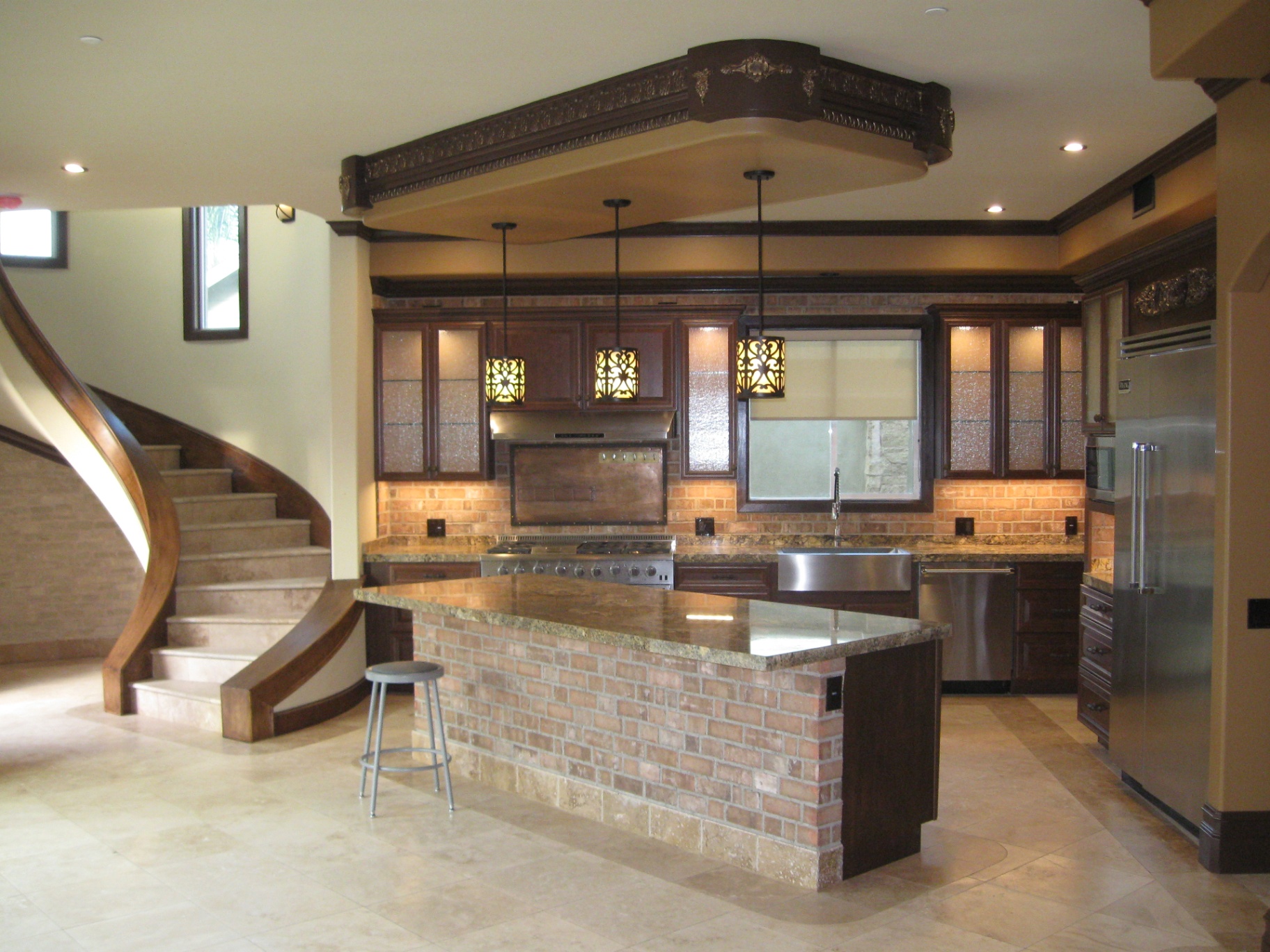 Custom Huntington Beach home kitchen with decorative pendant lighting, in-cabinet lighting, and recessed cans over granite island