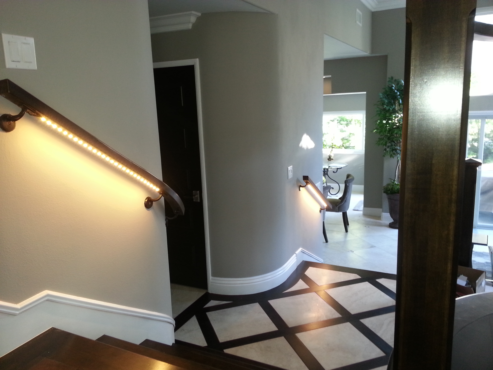 Illuminated LED handrail lighting on a residential staircase with custom inlaid tile flooring